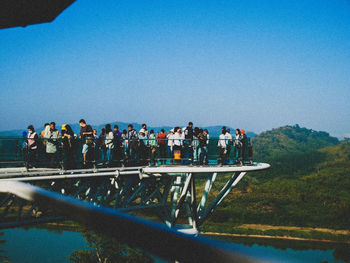 People on shore against clear blue sky