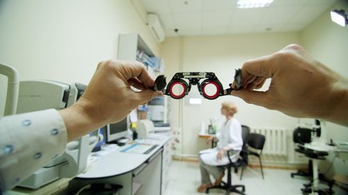 Optical eyeglass frames close-up, ophthalmologist examining patient with optometrist trial frame