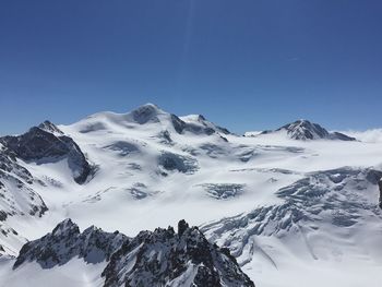 Scenic view of snowcapped mountains against clear blue sky