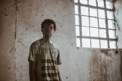 Young man standing against wall of abandoned building