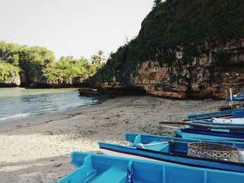 Boats moored on sea against clear blue sky