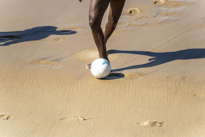 Lower body of a man with a ball on the sand at farol da barra beach in salvador, bahia, brazil.