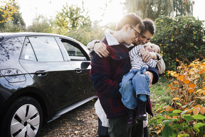 Father and mother playing with daughter near electric car during picnic