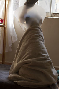 Rear view of woman sitting on bed at home