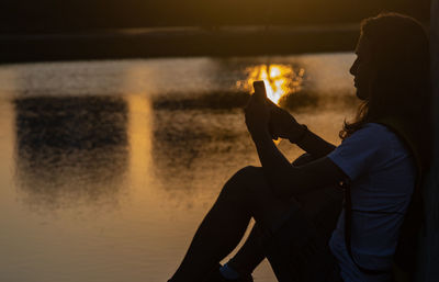 Side view of man smoking cigarette at beach during sunset