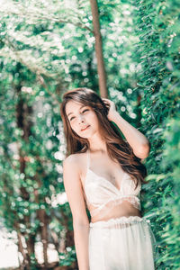 Young woman standing against tree