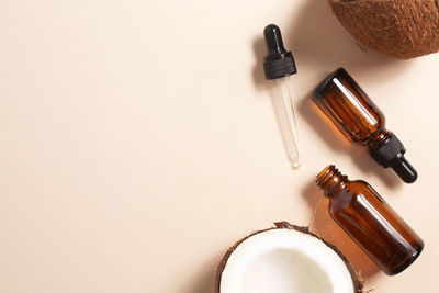 Bottles of coconut oil and fresh coconuts on beige background. coconut natural cosmetics.
