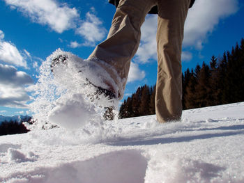 Person walking in a snow covered field, foot prints snow, sunny winter day