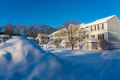 Snow covered houses and buildings against clear blue sky