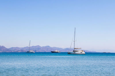 Sailboats sailing in sea against clear blue sky