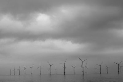 Wind turbines on field against sky