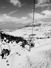 People on ski lift at snow covered field