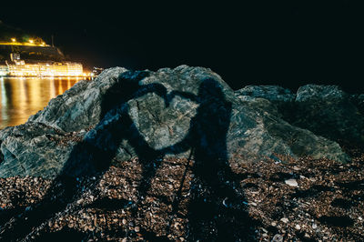 Aerial view of illuminated city by sea against sky at night