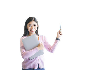 Portrait of smiling young woman standing against white background