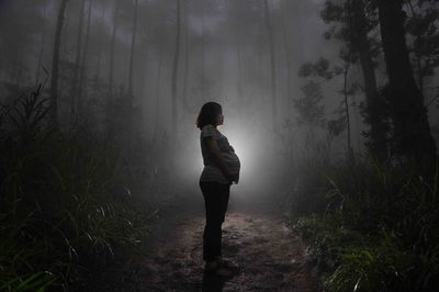 Full length of man standing in forest during foggy weather