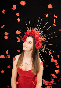 Portrait of beautiful young woman standing against red wall