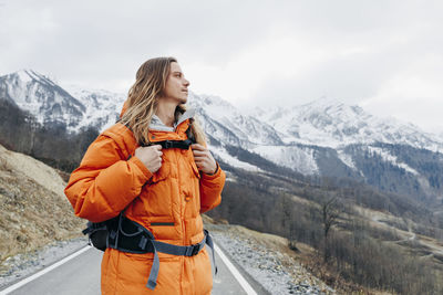 Contemplative man in orange jacket at winter vacation