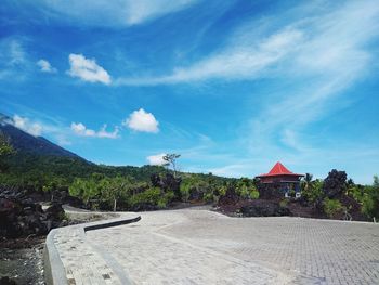 Footpath amidst trees and buildings against sky