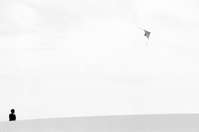 Low angle view of boy flying kite against clear sky