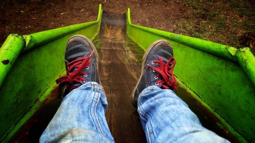 Low section of man sliding on slide at playground