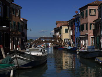 Boats moored in canal against sky in city