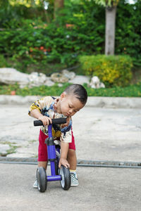 Full length of cute boy riding bicycle on road