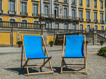 Empty chairs and tables in street against buildings