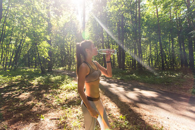 Woman standing by trees in forest