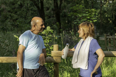 Senior men and woman looking to each other chatting and smiling after working out in a nature