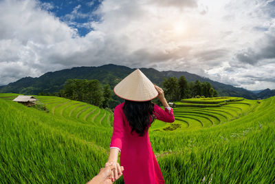 Rear view of woman standing on field against sky