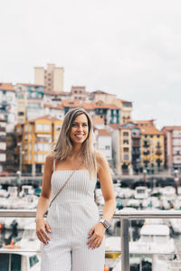 Portrait of smiling young woman standing against building