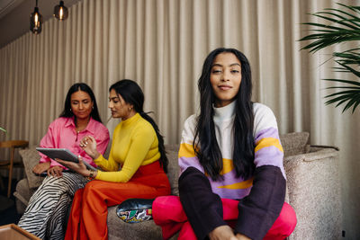 Portrait of female entrepreneur with colleagues sitting on sofa at office