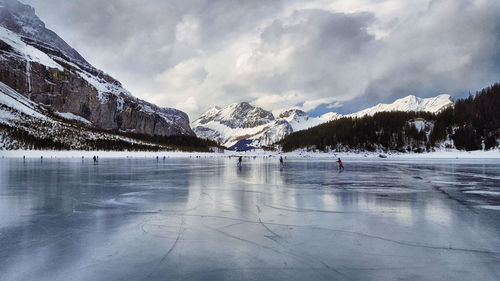 People skiing on frozen lake against sky