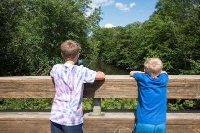 Rear view of boys standing against railing