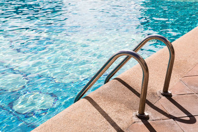 Blue water of swimming pool and grab bars ladder in hotel, swimming pool ladder, sunshine