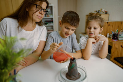 Mom and children at home are conducting an experiment with a volcanic eruption.