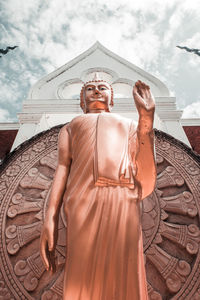 Low angle view of statue against building against sky