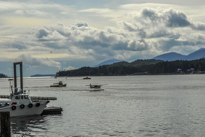 Boats in sea against cloudy sky