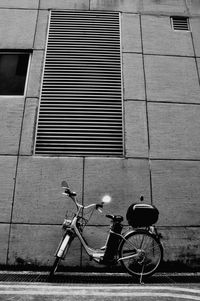 Bicycle parked on footpath against building