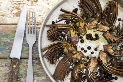 Presentation of a side dish based on sliced and baked artichokes with berries