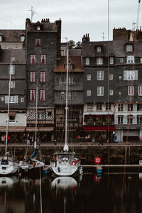 Boats moored on river by buildings in city