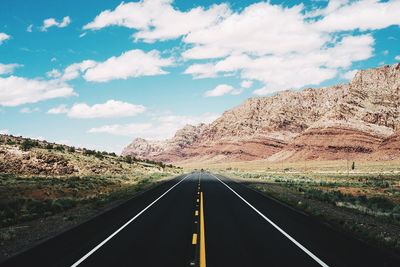 Empty road by mountains against sky