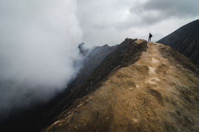 Person standing on mountain against sky