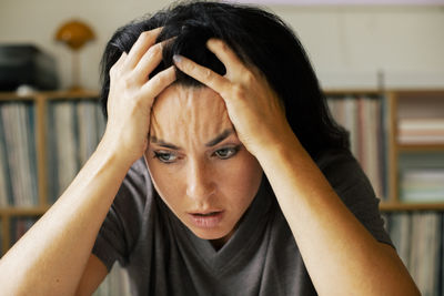 Stressed woman with head in hands at home