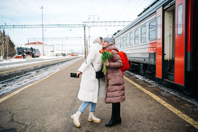 Girls say goodbye hugging on the station platform