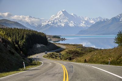 Road by snowcapped mountains against sky