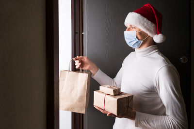 Safe christmas and new year at home, man in santa red hat and protective mask during coronavirus