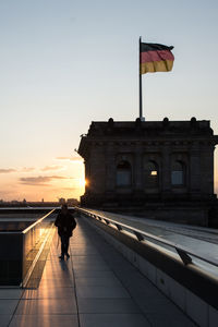 Man walking in flag against sky during sunset