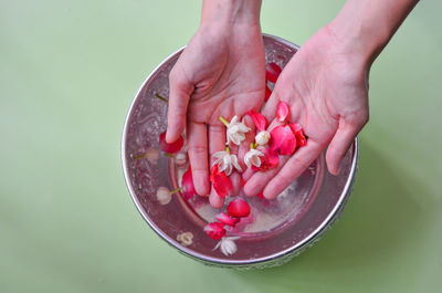 Close-up of hand holding strawberry over white background