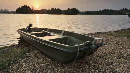 Boat moored at lakeshore during sunset